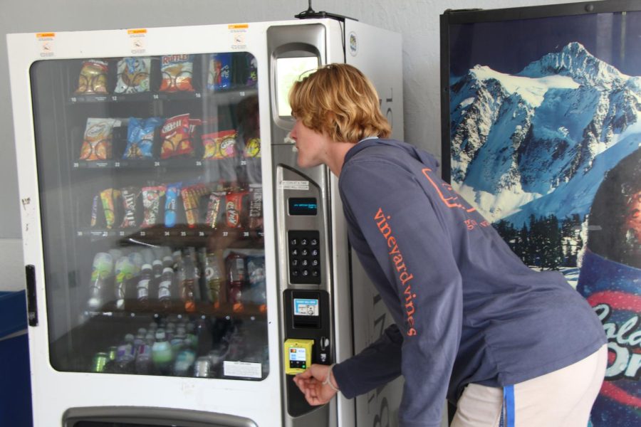 Senior Walker Buchanan inserts his credit card to buy a drink during his study hall. During lunch and Community Block, there is a line at the vending machines.Students enjoy being able to buy a snack or drink of their choice from the vending machine’s wide array of options throughout the day. The vending machines were so popular that the Upper School decided to place another vending machine in the gym lobby.