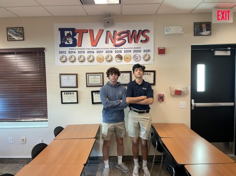 Senior Nate Samarias (left) and junior Zach Neidoff (right) pose in front of BTV's banner of accolades in Room 149. Since 2013, the production has garnered six first place finishes from the National Scholastic Press Association.