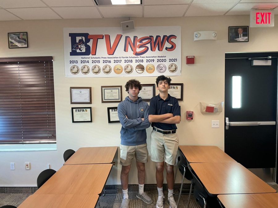 Senior Nate Samarias (left) and junior Zach Neidoff (right) pose in front of BTVs banner of accolades in Room 149. Since 2013, the production has garnered six first place finishes from the National Scholastic Press Association.
