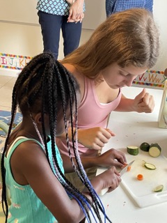 While volunteering at the Holy Ground Organization, sophomore Vanessa Zito teaches one of the children how to cut vegetables.
