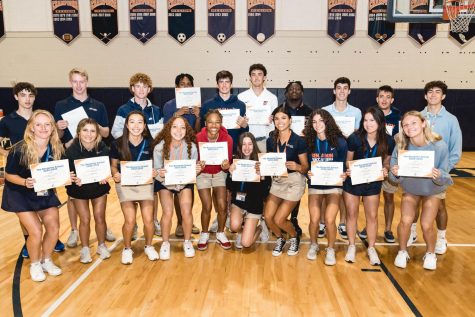 All of the athletes from boys wrestling, girls and boys soccer, and girls and boys basketball line up for a photo with their awards after the assembly.  
