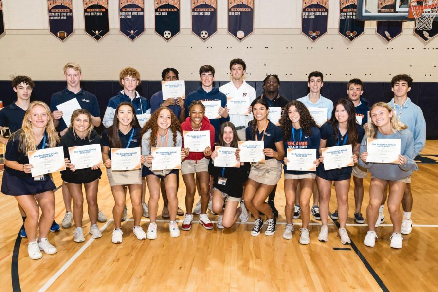 All of the athletes from boys wrestling, girls and boys soccer, and girls and boys basketball line up for a photo with their awards after the assembly.  
