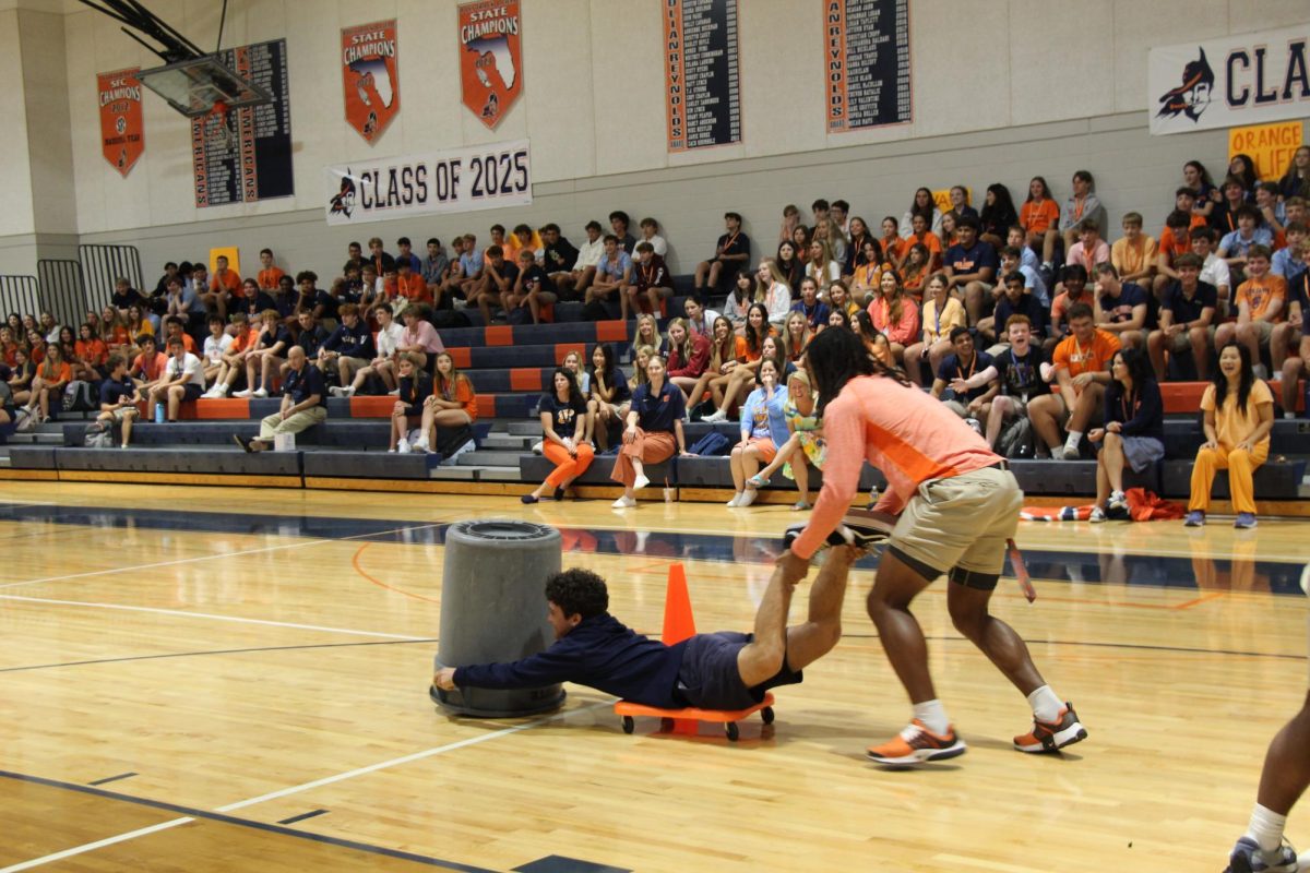 Senior Jacob Cosbey-Mosely holds up senior Michael Louis’s feet while they both try to collect as many balloons as they can for the Orange team during the Hungry, Hungry Hippos game. (Caroline Groffman)
