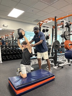 Coach Barrett Saunders instructs senior, Jacob Heilpern, in his weight lifting to instill the correct form in his students. Photo by Stella Liberman.