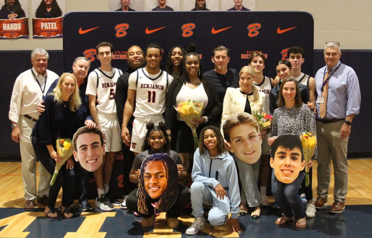 Senior members of the Varisty basketball team take a photo with their families, Head of School Mr. Faus, and Head of Upper School Mr. Carr.