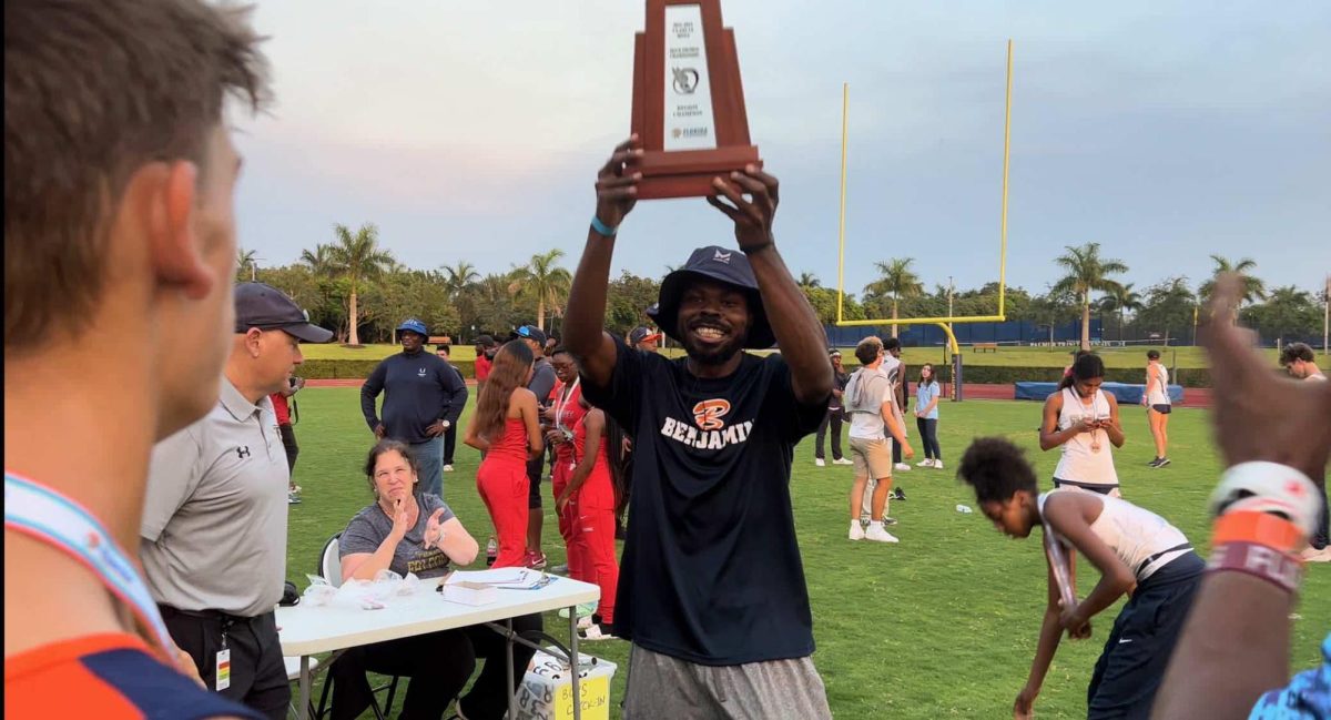 Coach Saunders holds up a trophy with the team. (Photo courtesy of Anna Malone)