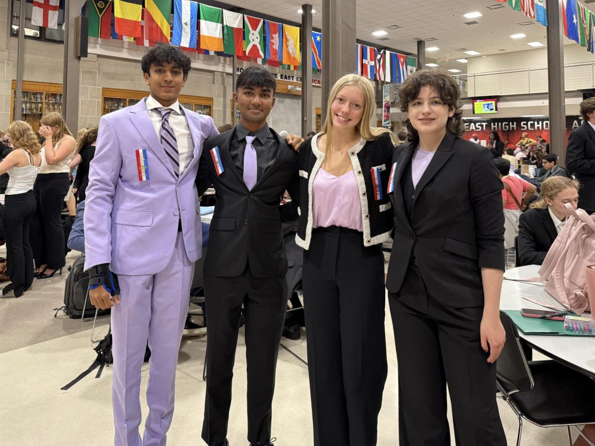 In the middle, seniors Dev Maharaj and London Allen stand alongside their fellow team members from the World Schools Debate event